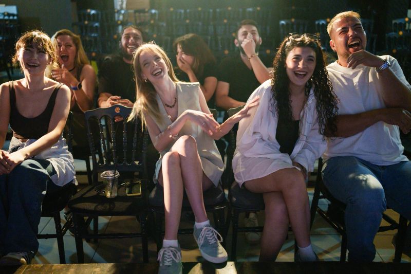 Happy spectators seated close together, laughing and reacting positively while watching a live show. Concept of fun, entertainment, and group enjoyment.