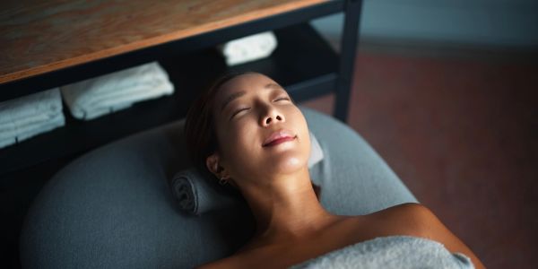 Woman relaxing with eyes closed on massage table.
