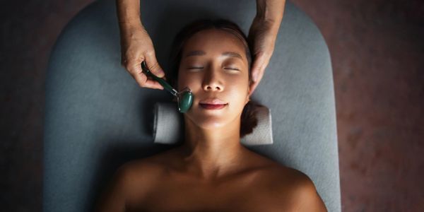 Woman receiving a facial massage with a jade roller.