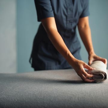 Person rolling a towel on a bed or massage table.