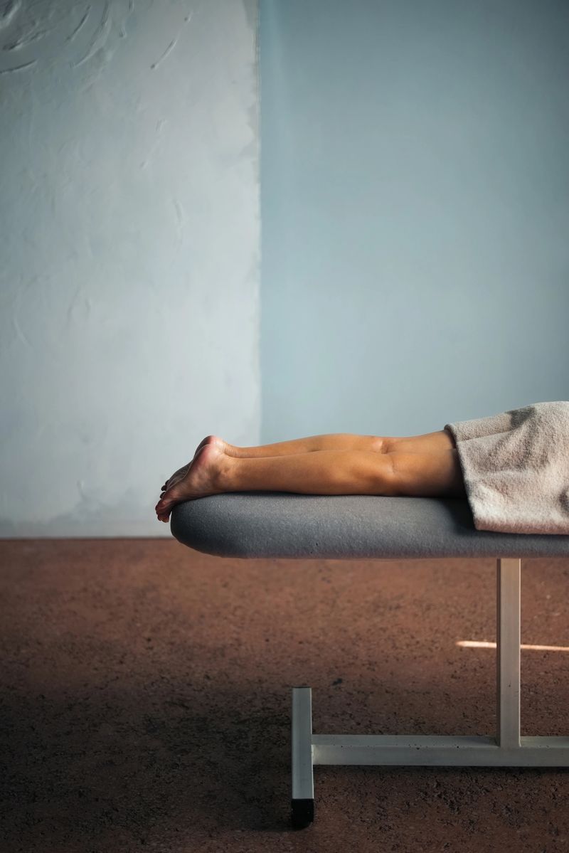 A serene image of legs resting on a cushioned bench. The minimalist setting with earthy tones highlights relaxation and comfort, cultivating a peaceful, rejuvenating ambiance in a spa or wellness environment.