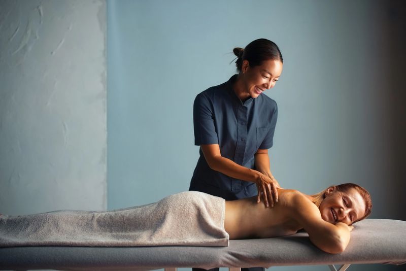 A massage therapist provides a relaxing back massage to a cheerful client, illustrating relaxation, wellness, and professional spa services in a calming atmosphere.
