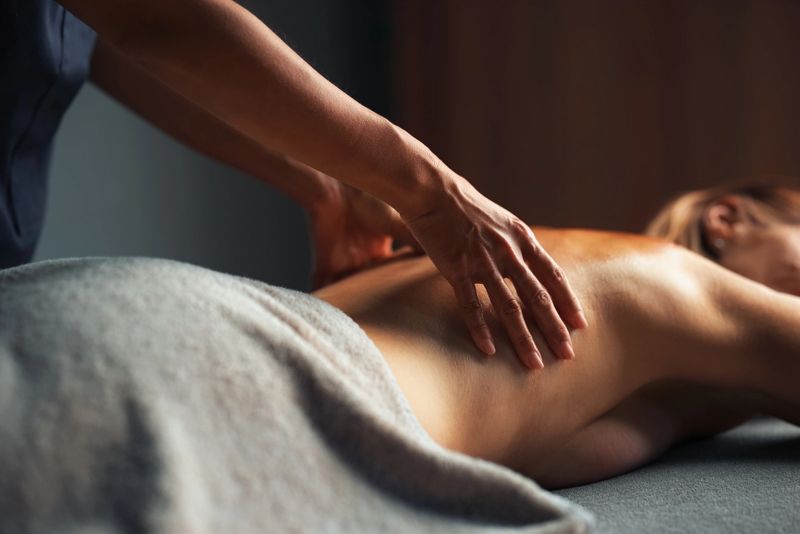 Hands performing a soothing massage on a person's back, promoting relaxation and wellness in a serene spa environment.