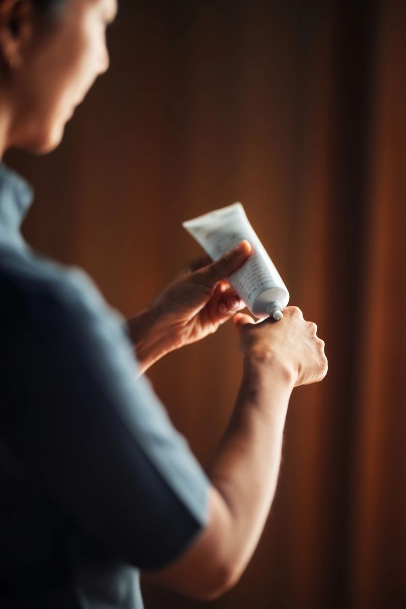 Close-up of a person squeezing cream onto their hand. This image represents self-care, skincare routines, and body care products. Its atmosphere is warm and intimate, emphasizing personal wellness.