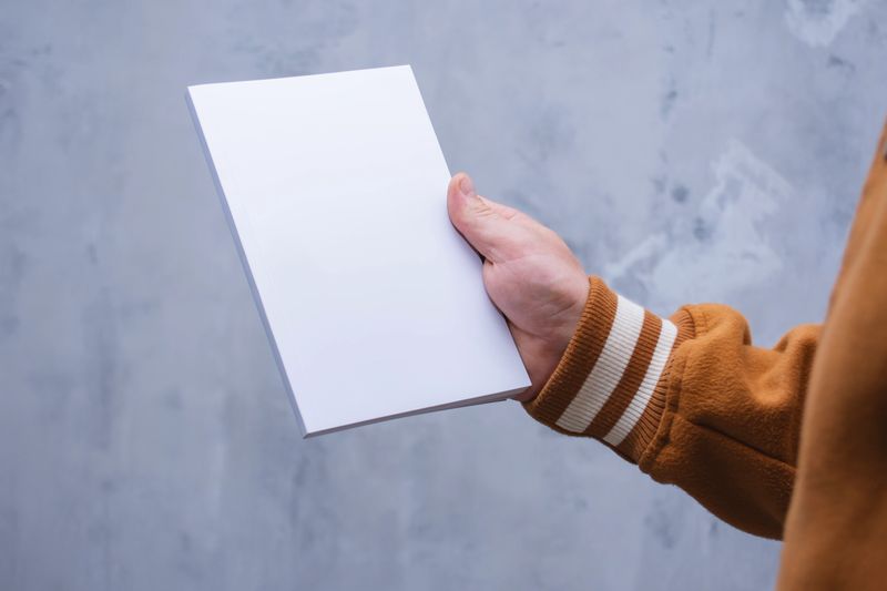 Realistic mockup of book cover, magazine in the hands of a man on concrete background. Concept for demonstrating editorial design, book covers and printed materials