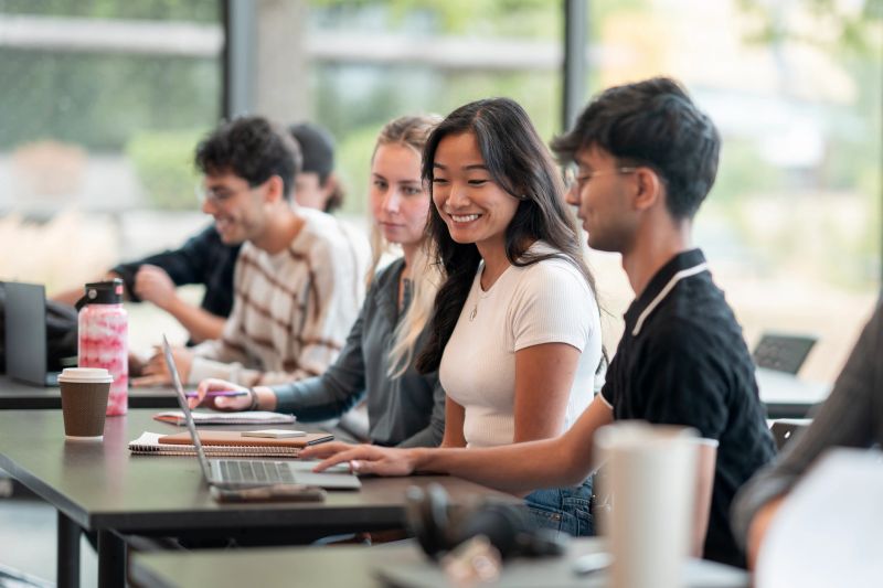 Engaged college students of diverse backgrounds collaborating on projects in a vibrant, well-lit classroom environment, fostering teamwork, communication, and creativity through active involvement and technology.