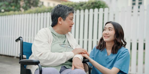 Caregiver comforting elderly woman in wheelchair.