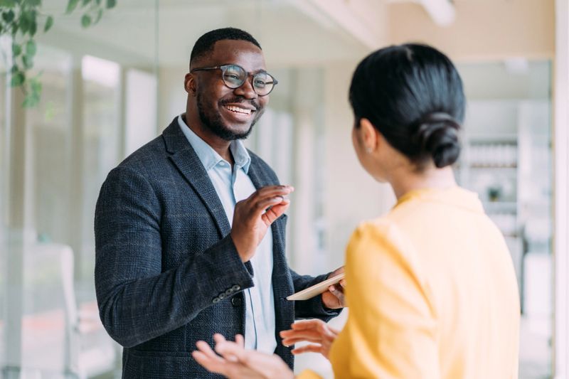 Shot of two coworkers having a discussion in modern office. Businessman and businesswoman in meeting using digital tablet and discussing business strategy. Confident business people working together in the office. Creative business persons discussing new project and sharing ideas in the workplace.