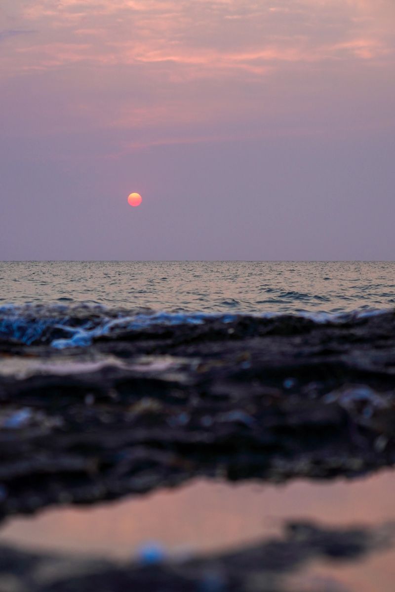 A breathtaking view of a sunset casting warm hues over the calm ocean waves, creating a peaceful and serene atmosphere, in Formentera