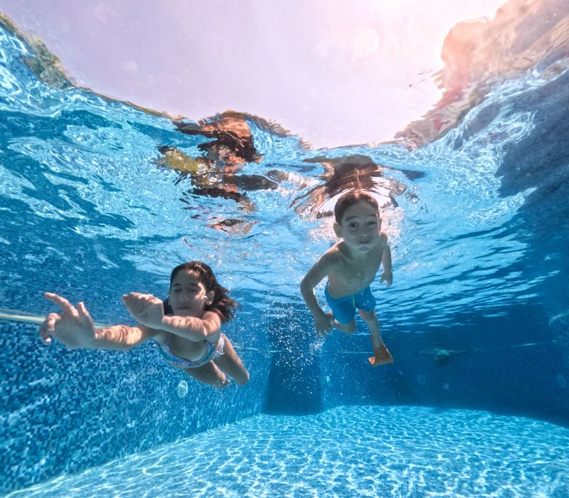 Kids swimming underwater. Sister and brother swimming underwater in a swimming pool.