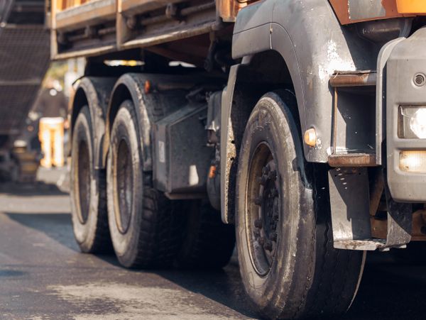 Close-up of a heavy-duty truck's rear wheels on a road.