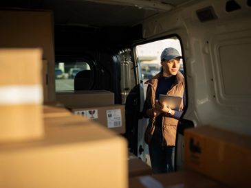 Woman checking packages inside a delivery van.