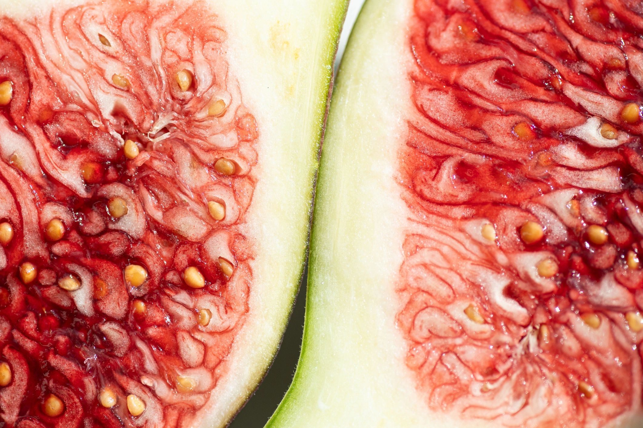 Nahaufnahme einer aufgeschnittenen Frucht mit roten und weißen Strukturen.