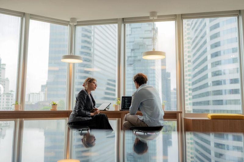 Advisor in modern office working on computer while speaking with clients. Corporate business, finance planning, trust, investment decisions, teamwork, leadership, and analysis of data and charts for success.