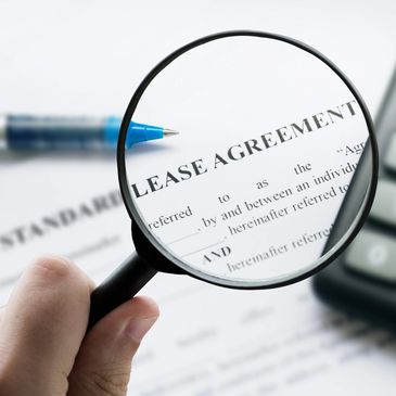 Magnifying glass focusing on the words 'LEASE AGREEMENT' on a document.
