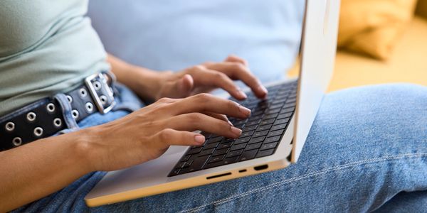 Person typing on a laptop while sitting comfortably.