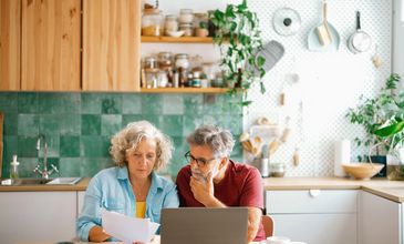 Senior couple reviewing documents together in a cozy kitchen.