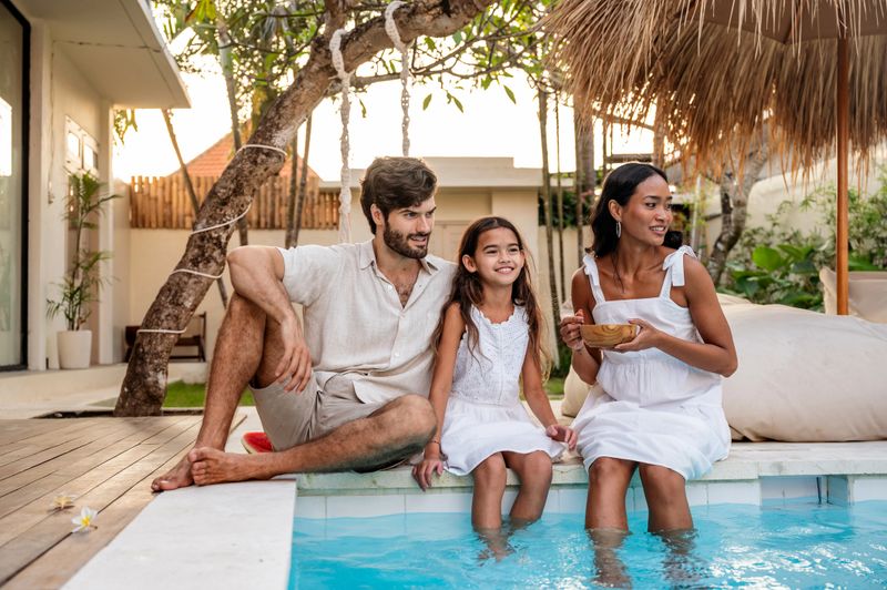A joyful family spending time together by a pool at a scenic holiday destination. The serene atmosphere, vibrant environment, and connection emphasize relaxation, enjoyment, and quality moments shared among loved ones.
