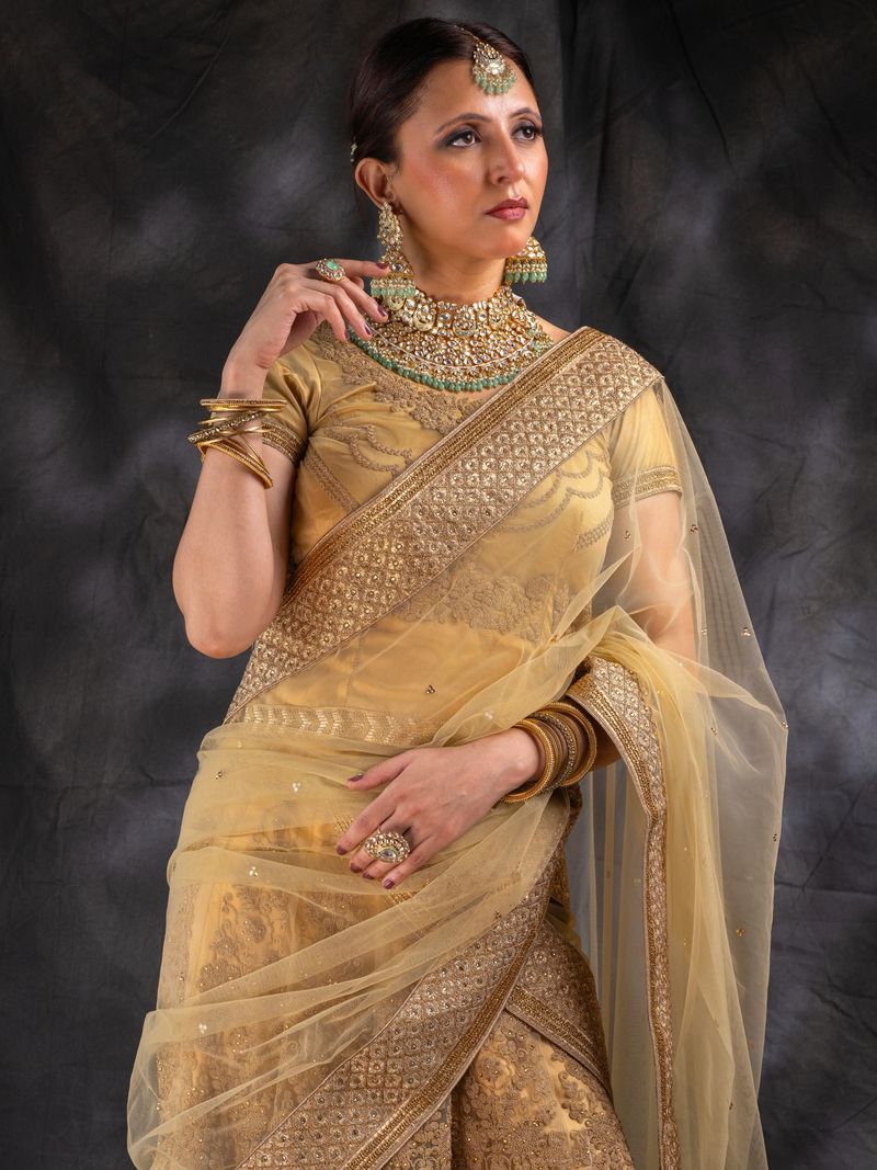 Portrait of beautiful woman in golden traditional attire and jewelry looking away and posing against black background