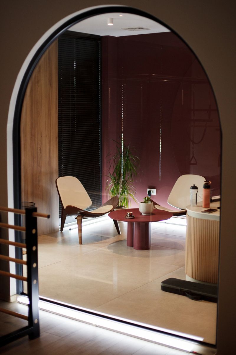 A stylish lounge area features minimalistic furniture, including a round table and two chairs, surrounded by plants and a warm atmosphere, perfect for relaxation and socializing.