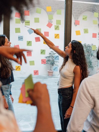 People collaborating with sticky notes on glass window.