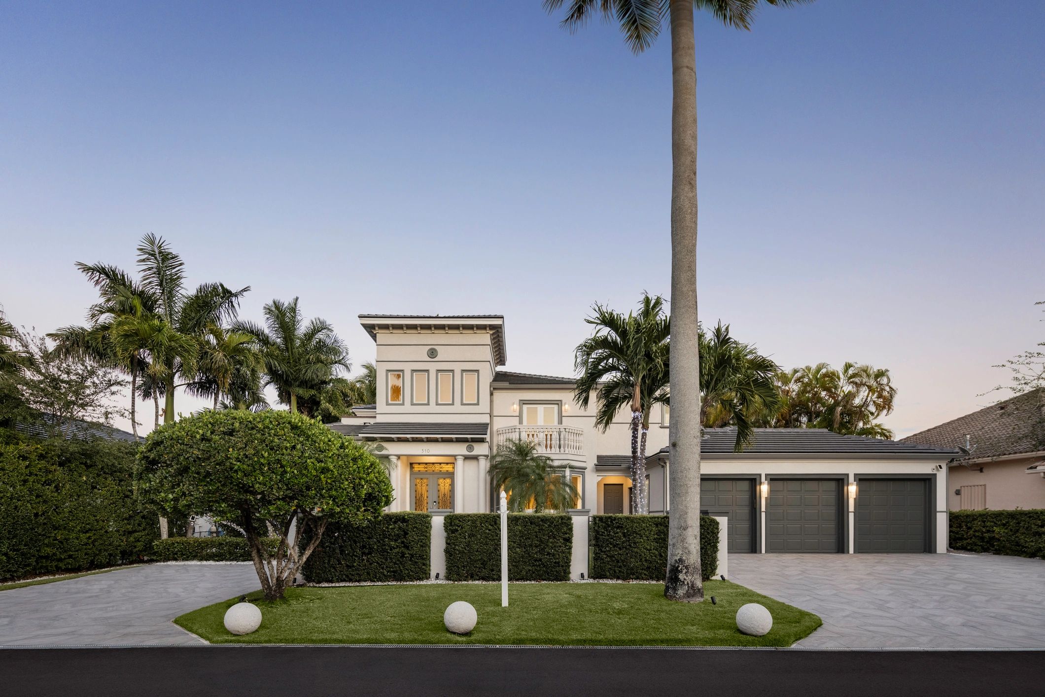Luxurious house with palm trees and a spacious driveway.