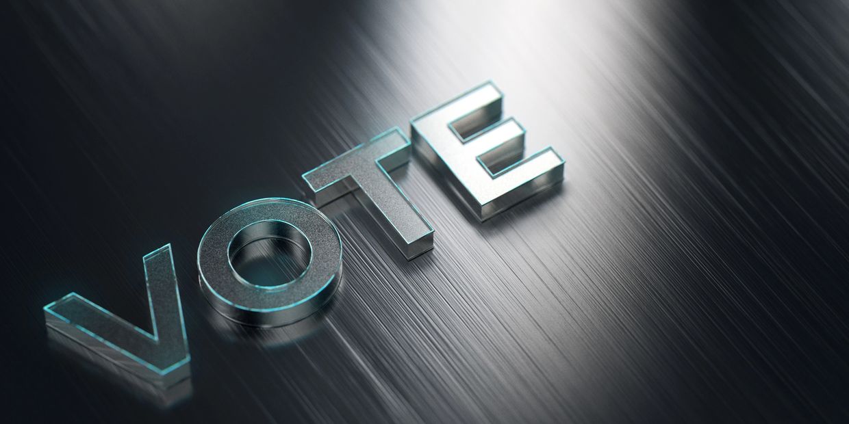 Glossy letters forming the word VOTE on a dark surface.
