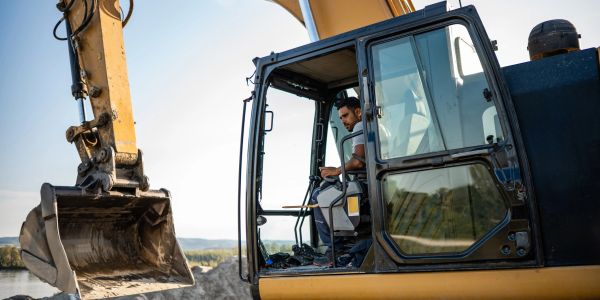 Man operating a yellow excavator outdoors.