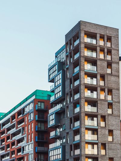 Modern apartment buildings with diverse architectural designs against a clear sky.