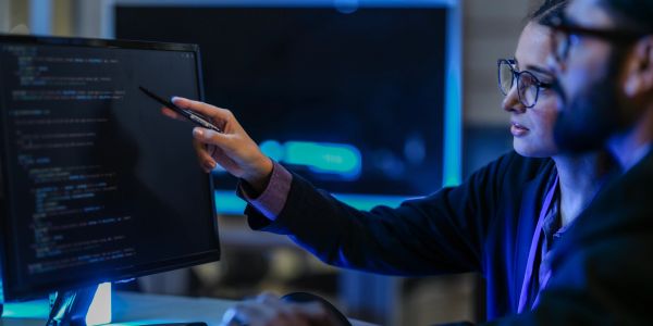Deux personnes analysant du code sur un écran d'ordinateur.