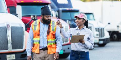 Two truck drivers discussing by trucks.