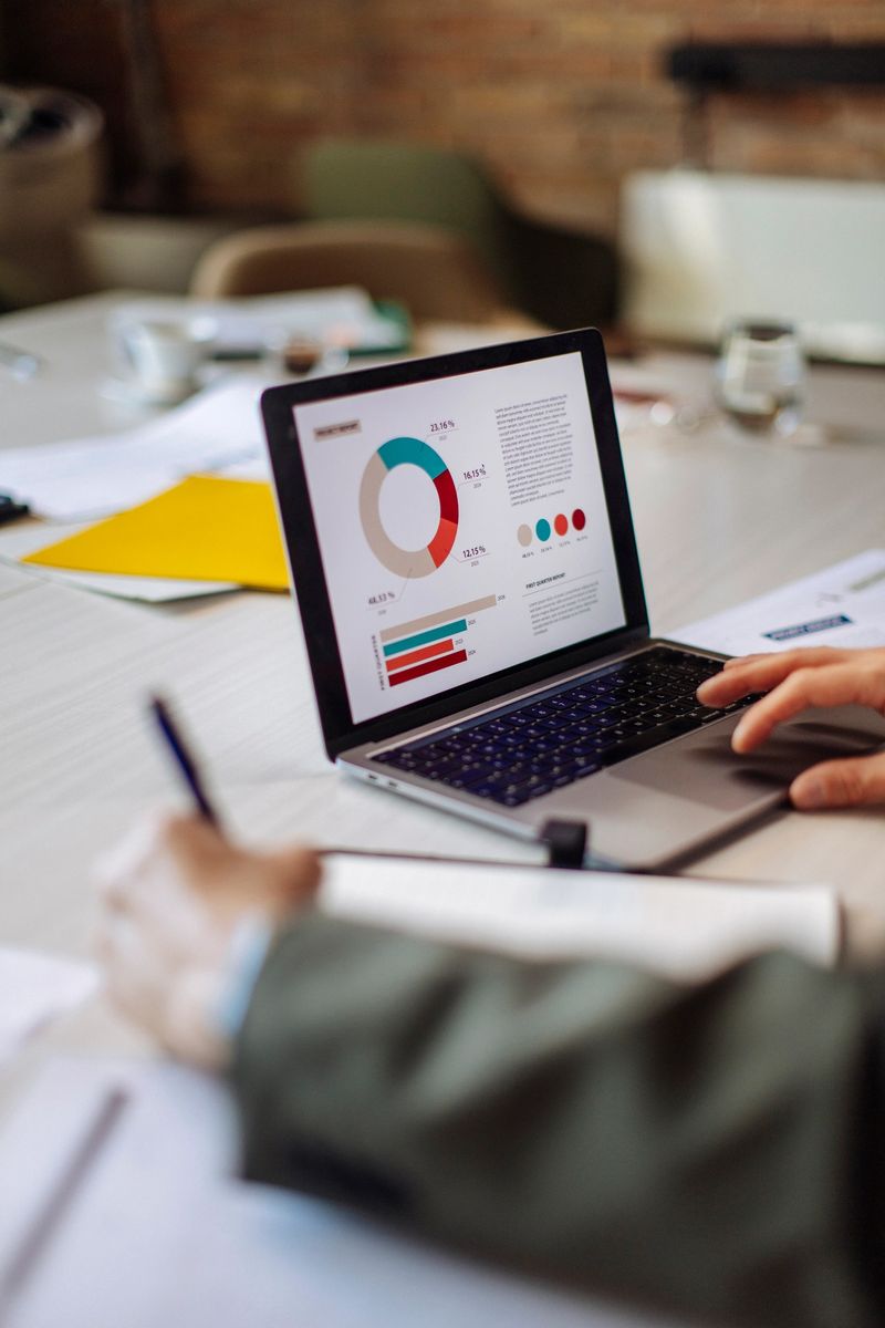 A professional closely examines data insights displayed on a laptop in a contemporary office; The environment conveys concepts of productivity and analytical decision-making