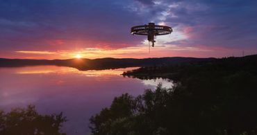 Sunset over a calm lake with a mysterious circular structure floating above.