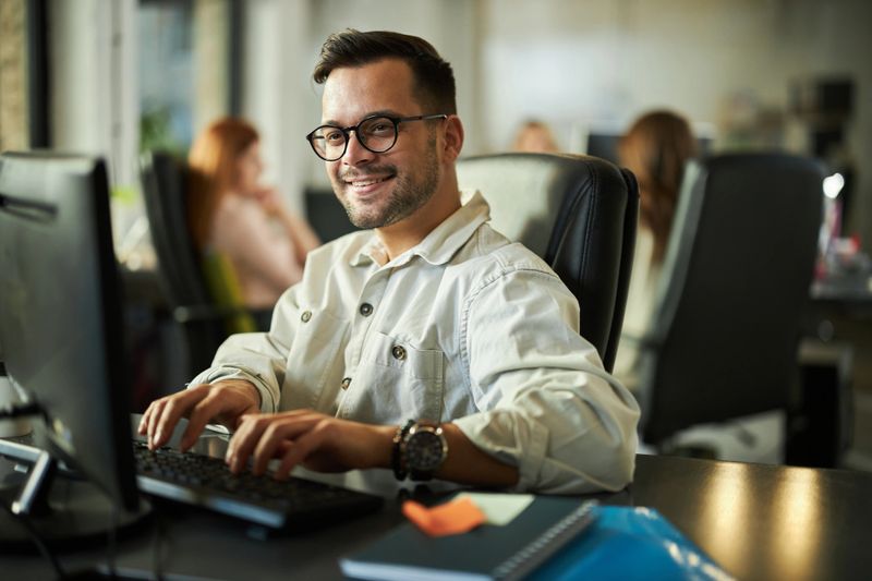 Young happy programmer coding a computer language on desktop PC in the office.