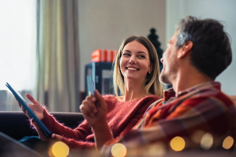 A man and woman share a moment, smiling and talking together in a comfortable home environment.