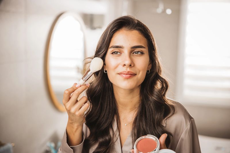 Young woman putting on makeup at bathroom.