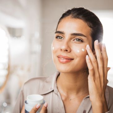 Woman applying face cream with a smile.