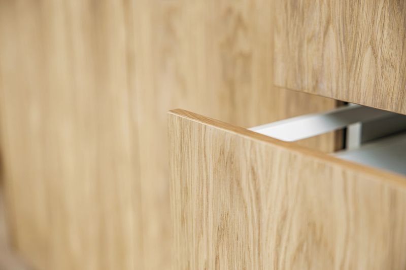 Close-up of modern wooden kitchen drawers, showcasing natural wood texture, minimalist design, and functional storage solutions for a clean and contemporary home interior