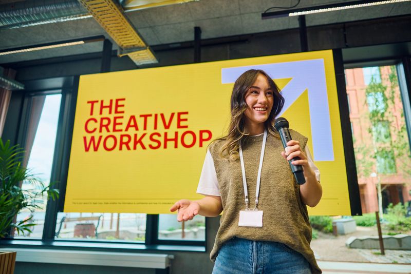 Young woman presenting her ideas at a creative workshop, holding a microphone and speaking passionately