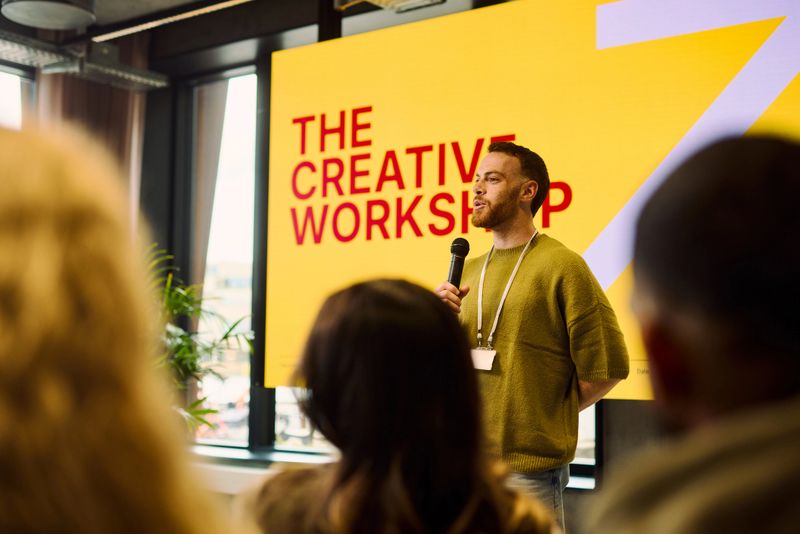 Young adult man speaking at a creative workshop, engaging the audience with innovative ideas