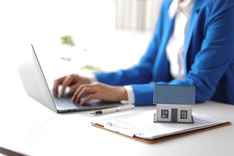 Businesswoman, real estate agent working on contract documents on laptop.