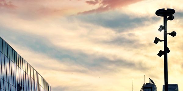 City skyline with reflective glass building at sunset under colorful sky.