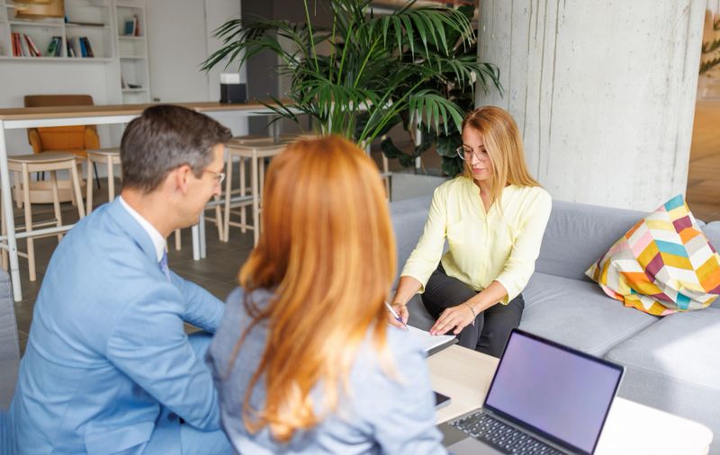 Businesswoman showing a contract to a couple during a meeting in a modern office