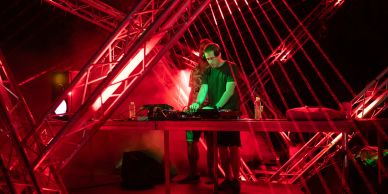 DJ playing music at a club with red lighting.