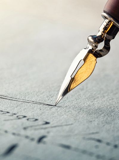 Close-up of a fountain pen tip writing on paper.