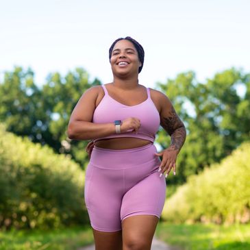 Woman jogging outdoors in pink workout clothes.