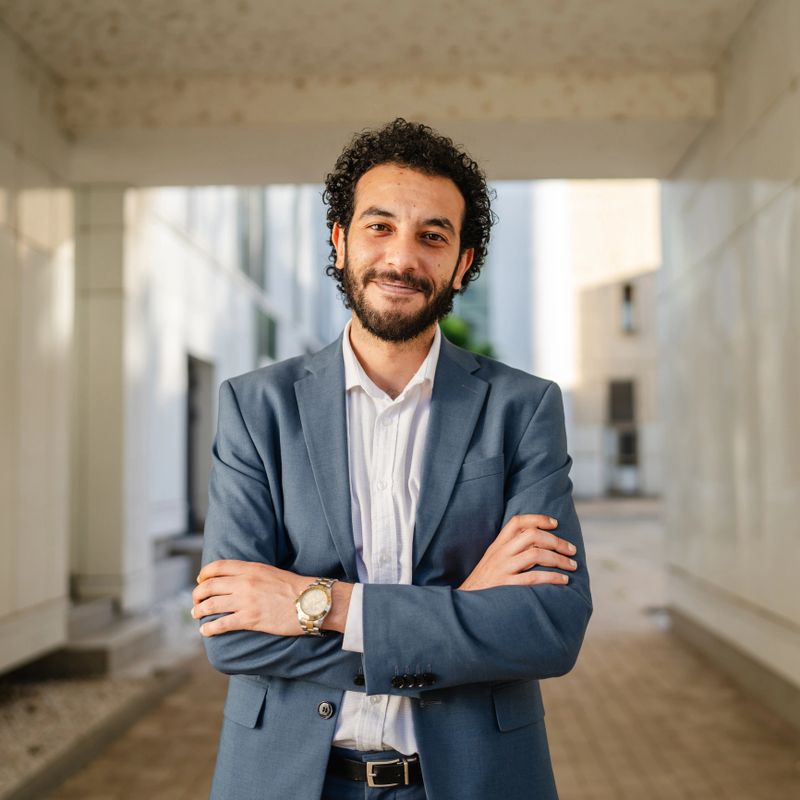 Confident businessman is smiling with crossed arms, exuding professionalism and success in a modern office building, showcasing leadership and achievement in corporate environment