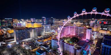 Night view of a city with a large illuminated Ferris wheel.