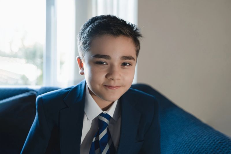 Portrait of confident schoolboy in uniform sitting indoors with natural light. Concept of Back to school, education, AI-based personalized and adaptive learning, smart future, and youth development