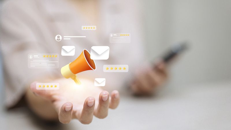Human hand holding digital hologram with megaphone, customer review stars, and email notifications. Concept of digital marketing, online promotion, and customer engagement.